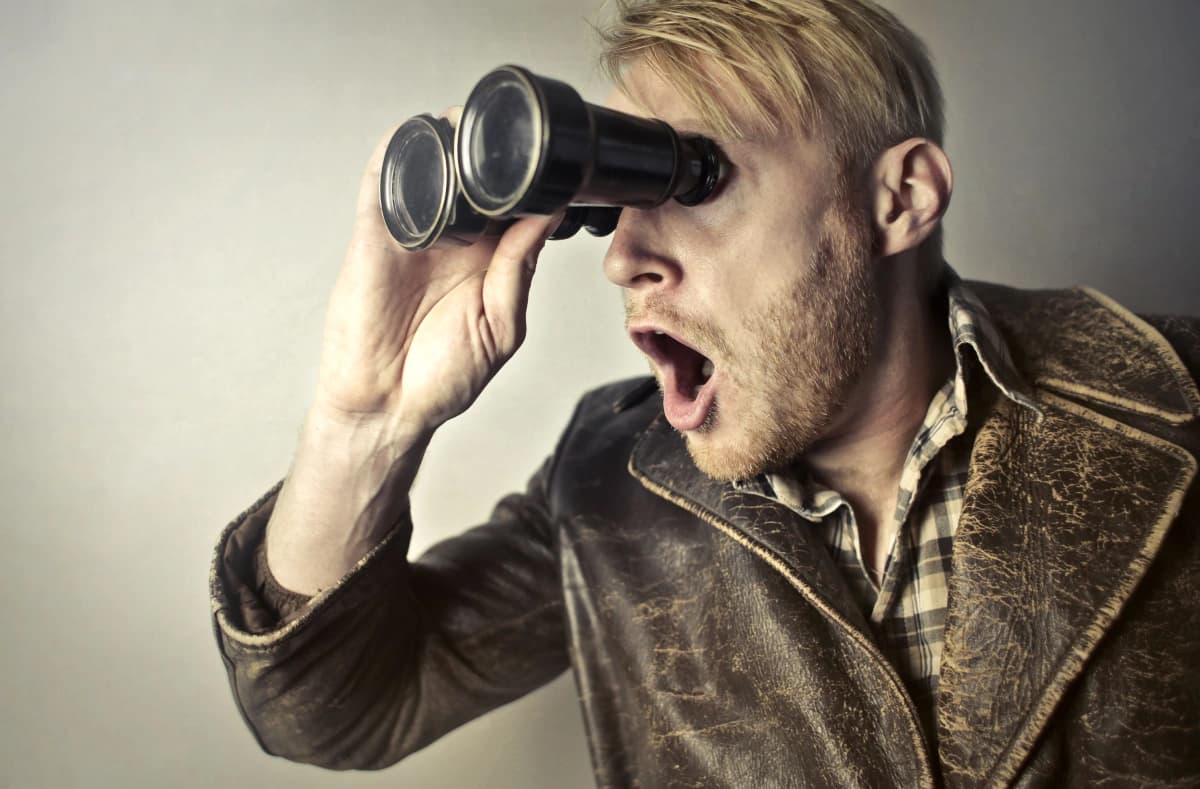 Person looking through binoculars to search for information and discover new opportunities online
